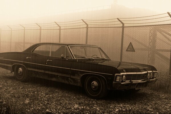 Cadillac en la niebla detrás de la valla de hierro