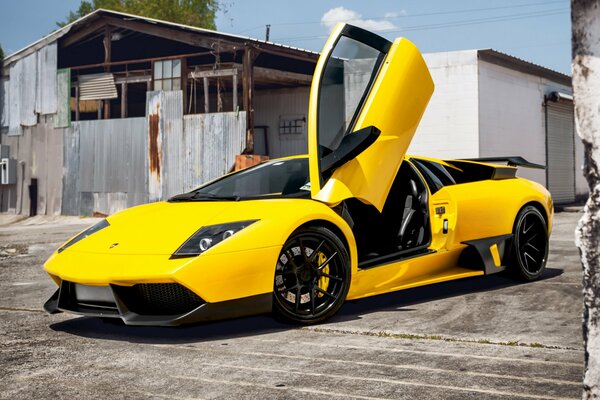 Yellow lamborghini murcielago on the background of an old barn