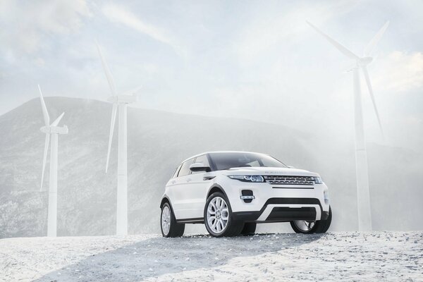 Rover Renge blanc sur fond de moulins à vent blancs, montagnes et ciel dégagé