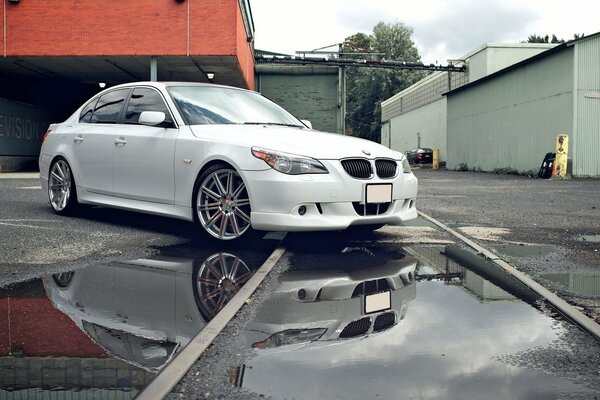 A white car is reflected in a puddle