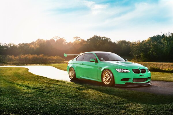 BMW verde en el resplandor en la carretera soleada