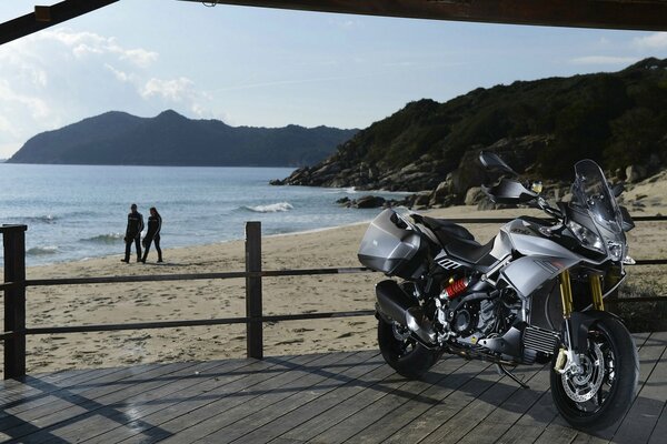 Foto eines Motorrads am Strand vor dem Hintergrund des Meeres und der Felsen