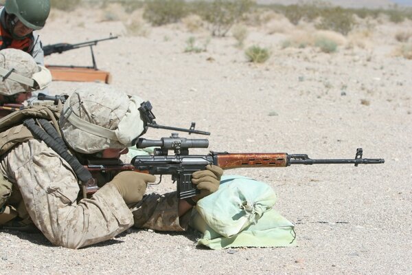 A soldier is lying on the ground with a machine gun