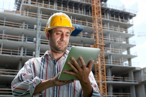 A man in a helmet holds a tablet