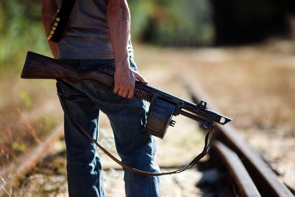 Homme avec des armes sur fond de chemin de fer