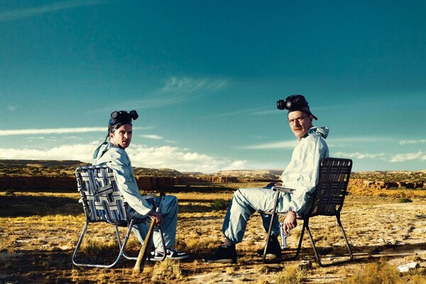 Dwóch mężczyzn w dziwnych ubraniach siedzi na pustyni