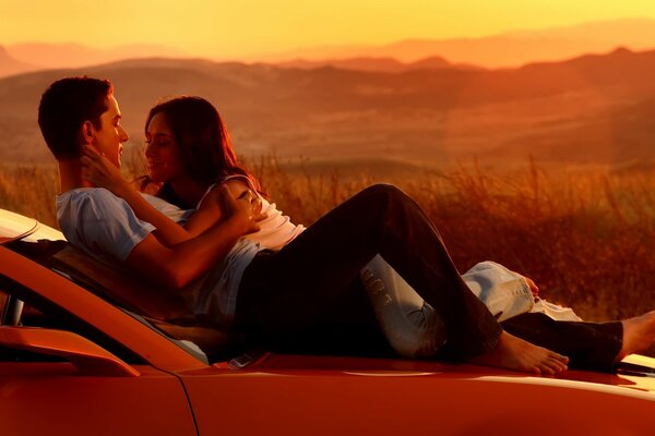 A couple in love at sunset by car