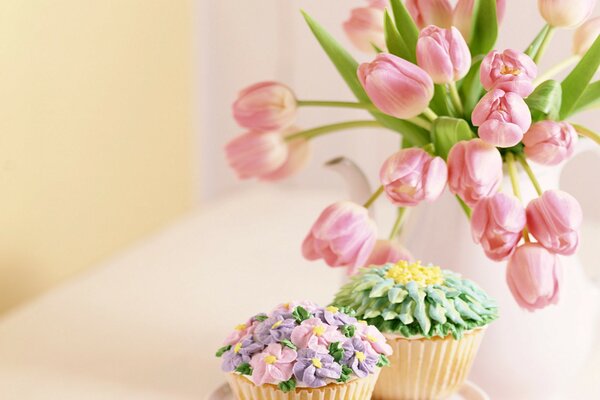 Tendres cupcakes sont debout sur la table avec un bouquet de tulipes dans un vase