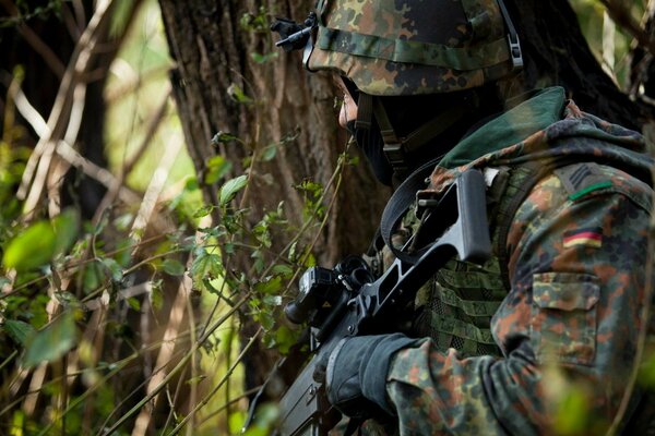 Солдат с оружием в лесу