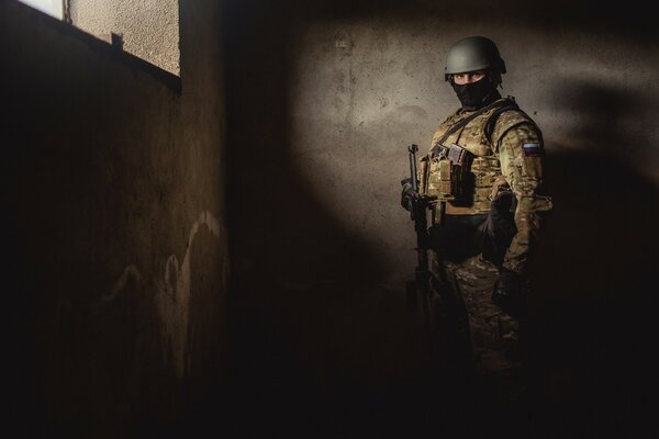 A special forces soldier stands at a concrete wall