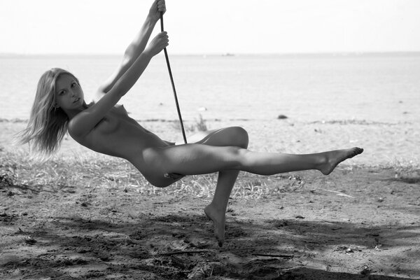 Naked girl swinging on the shore