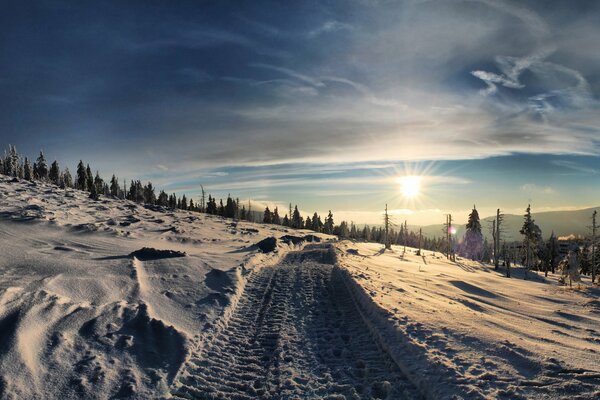 Soleil brillant et et la route au milieu de la neige