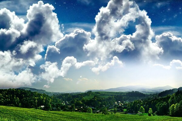 Fluffy clouds in the blue sky over a green village. Landscape