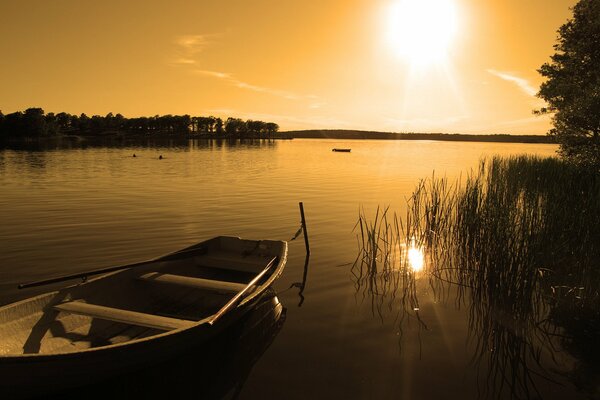 Boat on the shore of the lake in the sunset