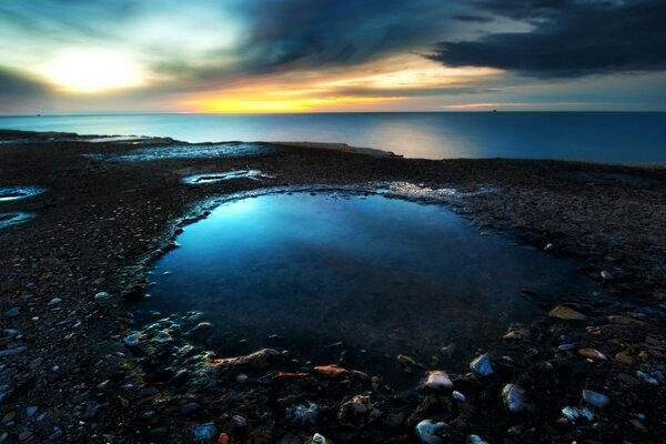 Playa rocosa y mar azul en los últimos rayos del atardecer