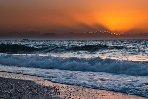 Vagues sur la mer au coucher du soleil sur la rive