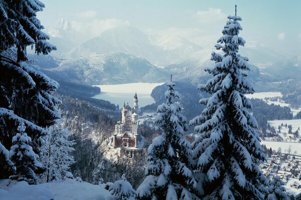 Ein Schloss inmitten von Bergen und schneebedeckten Pinien