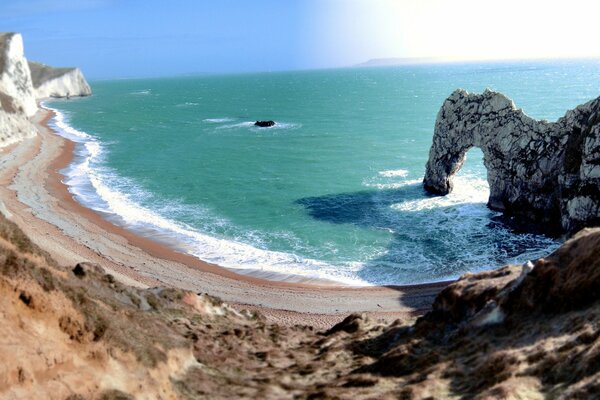 Lagoon, wild beach and azure ocean with a surf-beaten arch in the rock