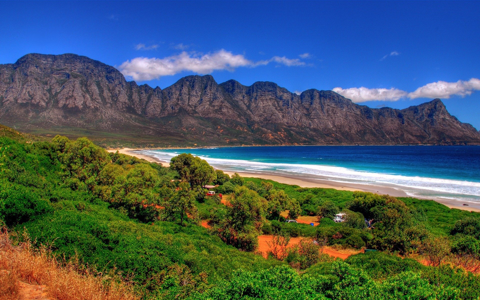 mare montagne erba schiuma cielo nuvole furgone bianco bastone gocciolante e un altro furgone bianco sabbia verde erba bruciata rocce piante rocce oceano acqua immagine paesaggio natura natura sfondo isola altopiani cielo aria vacanza