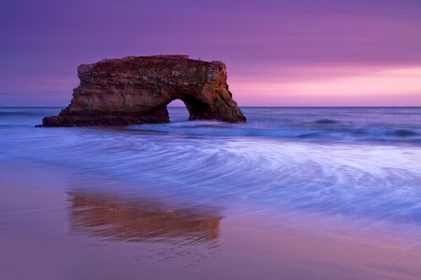 Roches dans la mer au coucher du soleil rose