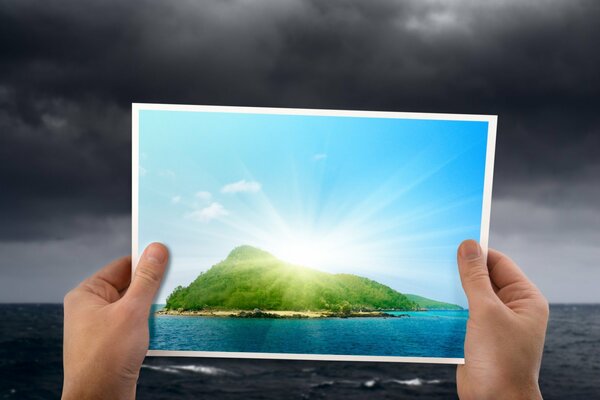 Las manos sostienen una foto de la isla en medio de una tormenta eléctrica