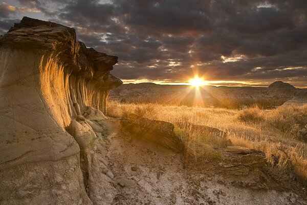 Sunset among the clouds at the rocky field