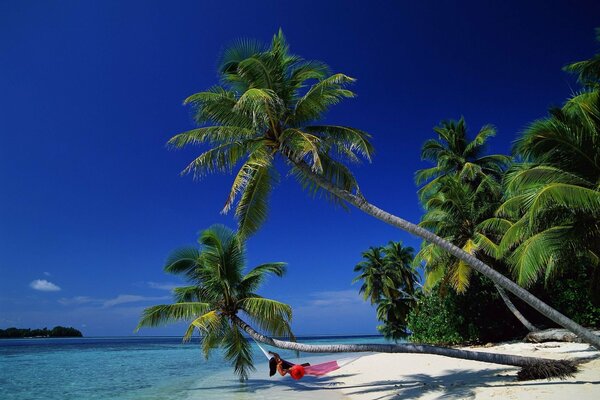 The girl in red is lying on a hammock