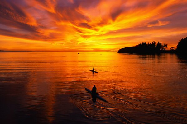 Swimmers on boats against the sunset