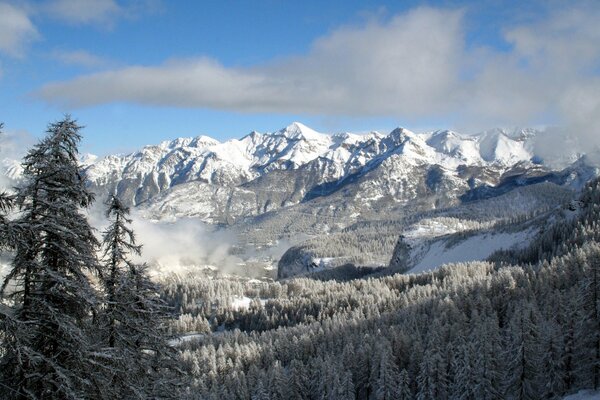 Nuvole nel cielo blu sopra le montagne innevate