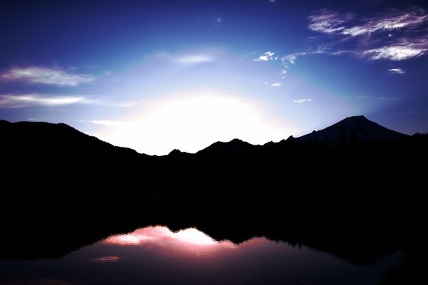 Black mountains and the sun reflected in the water