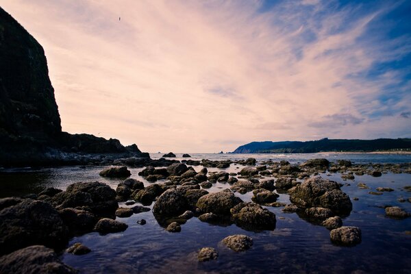 Muchas piedras en el agua contra el fondo de las montañas y el cielo