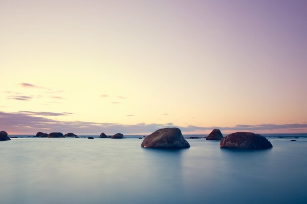 Puesta de sol en medio del mar y las piedras