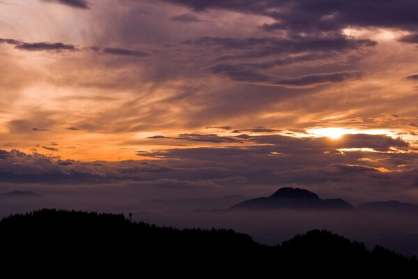 Schöner Sonnenuntergang hinter Wolken und Bergen