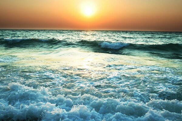 The evening sunset is reflected in the raging sea