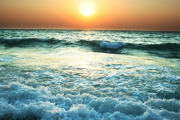 Le coucher de soleil du soir se reflète dans la mer qui fait rage
