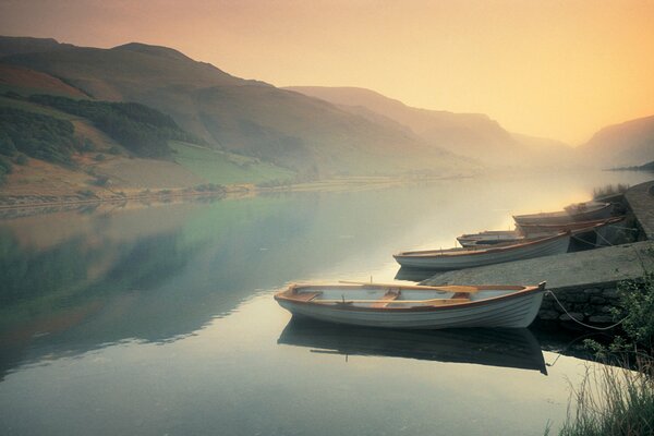 Boats are tied up in a pond against the background of misty mountains