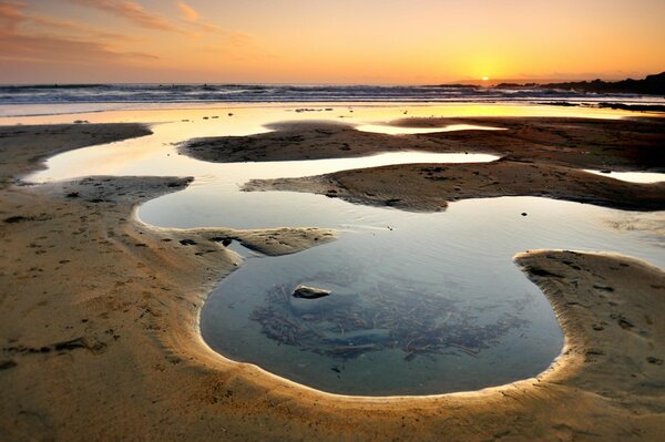 Wasser in Sandschalen bei Sonnenuntergang