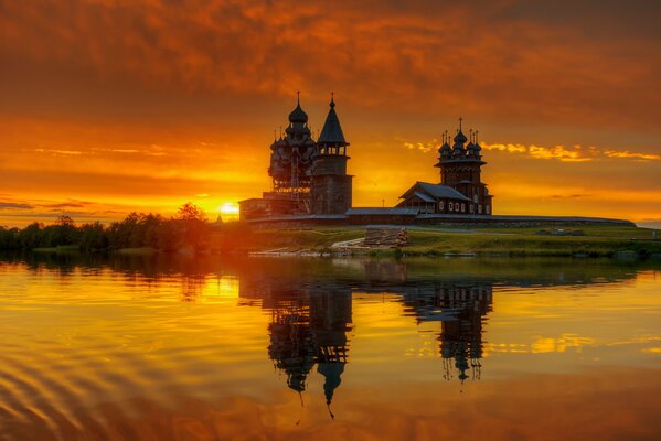 Wooden church in front of the lake at sunset