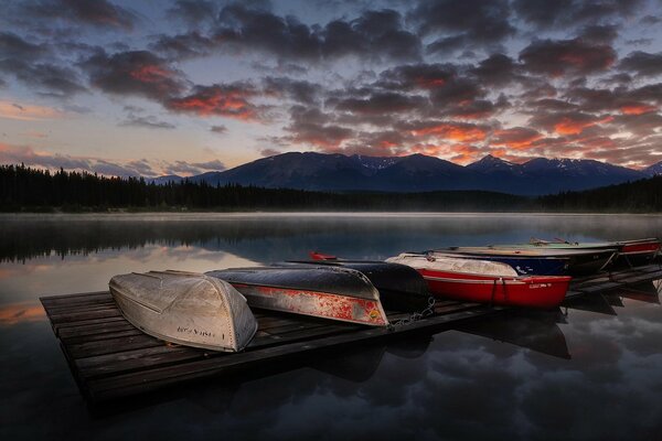 Перевернутый лодки на пирсе озера на закате