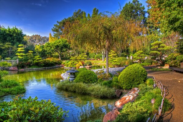 Gepflegter Garten mit Gehwegen von Bäumen und Sträuchern, Teich in Kalifornien, USA