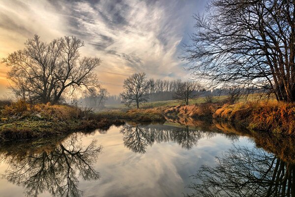 Papel pintado de otoño con el reflejo de los árboles y el cielo en el río