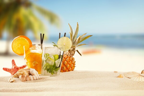 Summer tropical cocktails on the background of sand and sea surface