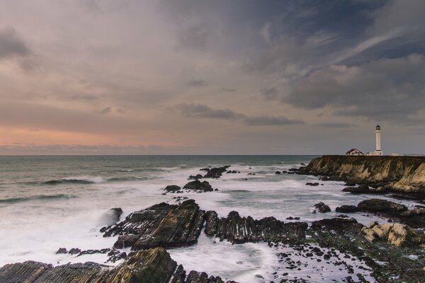 Ein Foto eines Leuchtturms. Schönes Foto von Felsen und Meer. Ein entfernter Leuchtturm am Ufer