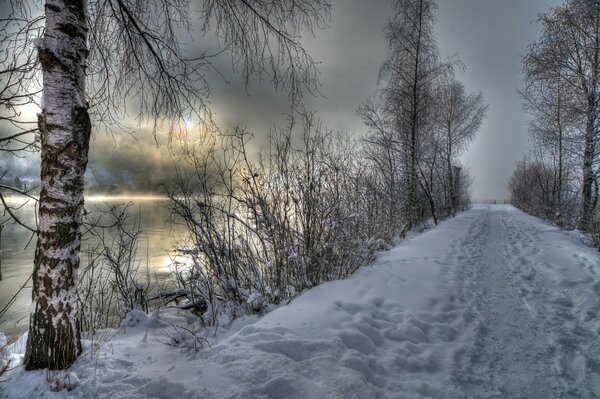 Route enneigée près de la rivière au coucher du soleil