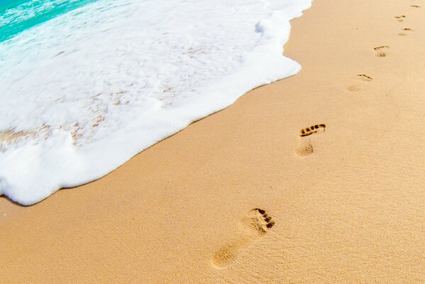 Footprints in the sand near the foam