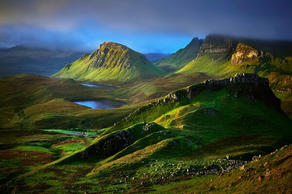 Hills covered with greenery and a blue expanse of water against an azure-misty sky