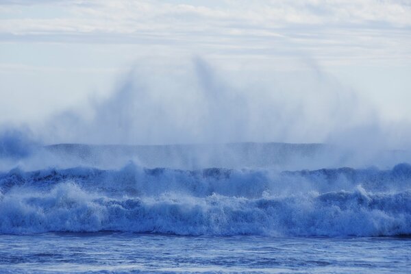 Ondas azules de espuma de mar triples con un montón de pequeñas salpicaduras