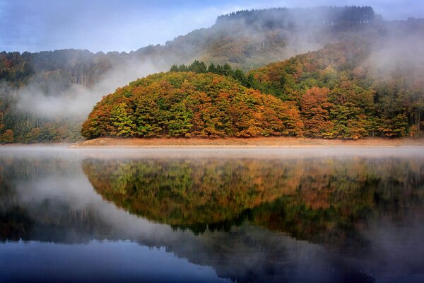 Der Herbstsee spiegelt die Bäume wider