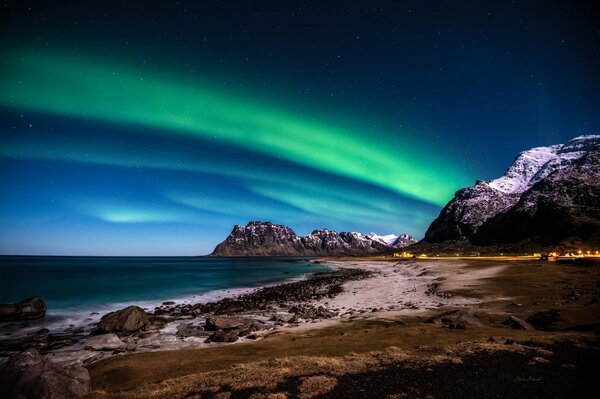 Luces del Norte en la orilla del mar en el fondo de las montañas