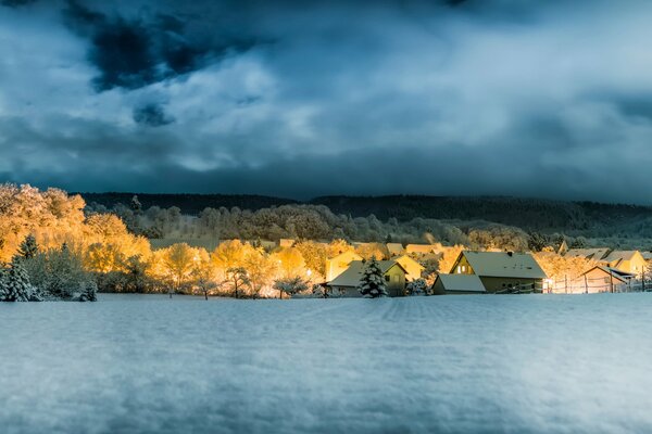 A forest with a village in front of the river and a stormy sky